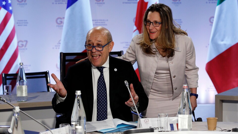 La ministre canadienne des Affaires étrangères, Chrystia Freeland, et le ministre français des Affaires étrangères, Jean-Yves Le Drain, sourient autour d'une table.  