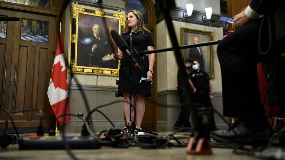 Chrystia Freeland steht inmitten von Drähten und Mikrofonen im Flur des Unterhauses in Ottawa.