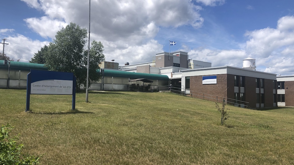 Une bâtisse brune au sommet de laquelle flotte le drapeau du Québec.