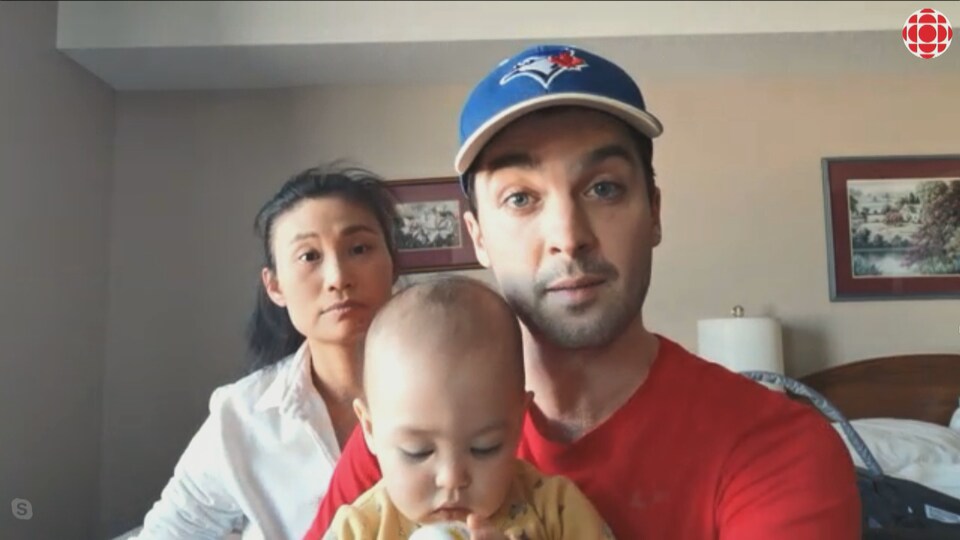 Un homme avec un bébé et une femme dans une chambre d'hôtel. 