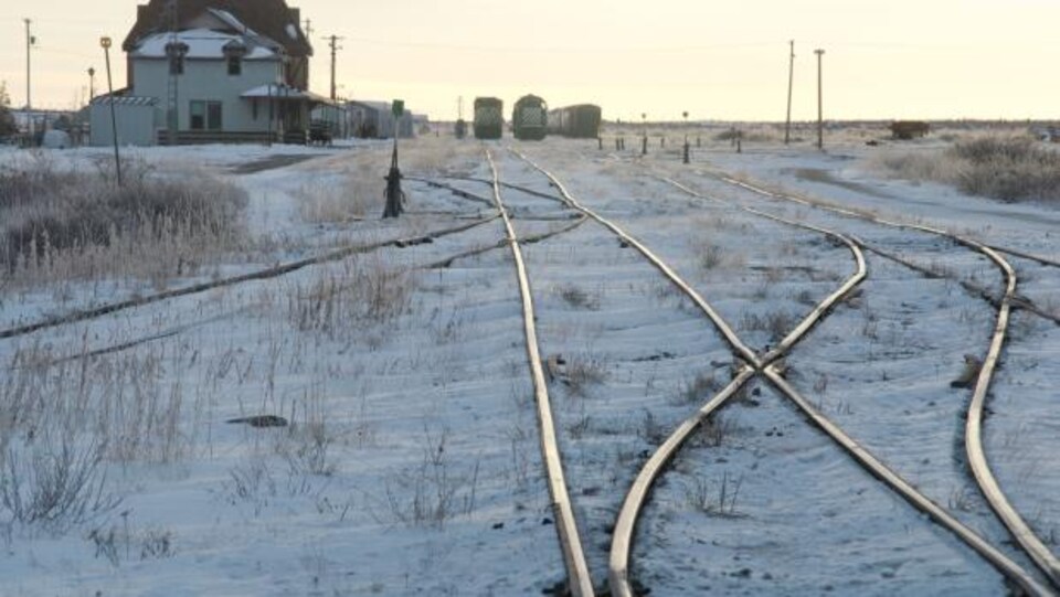 Des chemins de fer entourés de neige et des wagons au loin dans la ville de Churchill au Manitoba