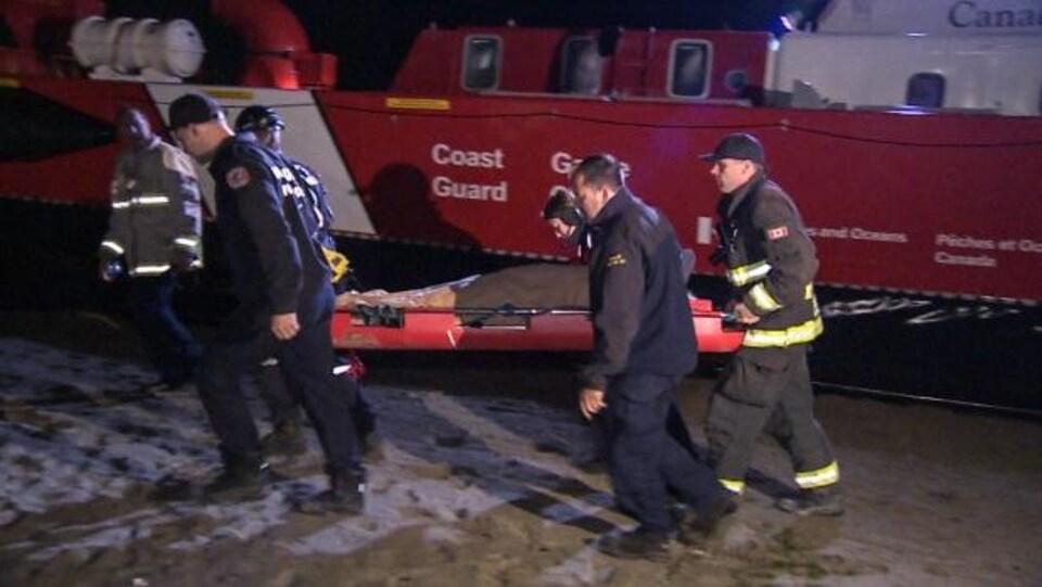 Les secouristes transportent sur une civière un homme qui a fait une chute d'une falaise près de Wreck Beach.