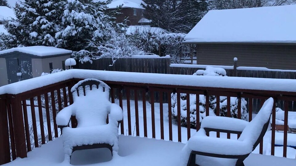Une cour arrière et une balcon recouverts de neige.