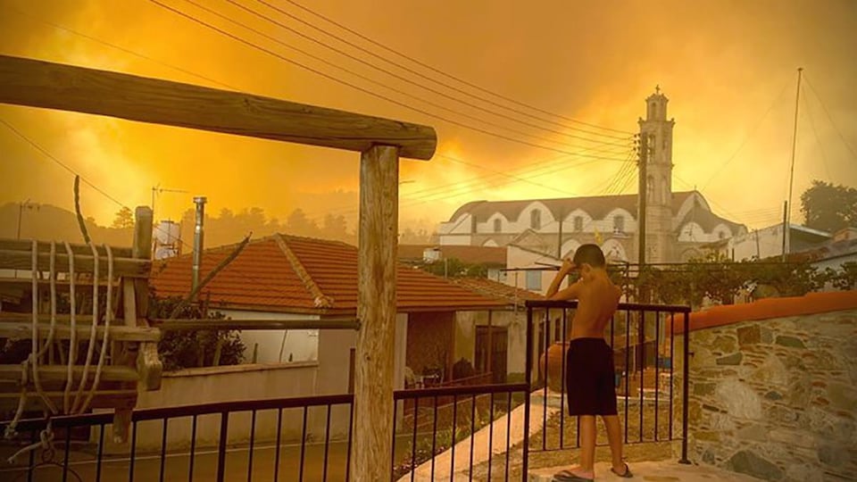 Un ciel jaune de fumée et de feu, avec à l'avant-plan des maisons