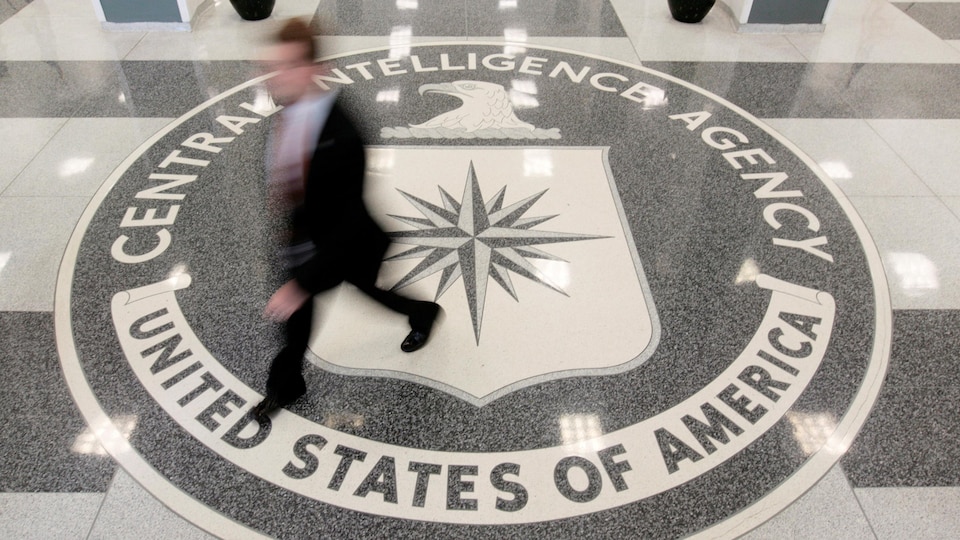 Un homme marche sur un immense logo de la CIA peint sur le plancher du siège social de l'agence.