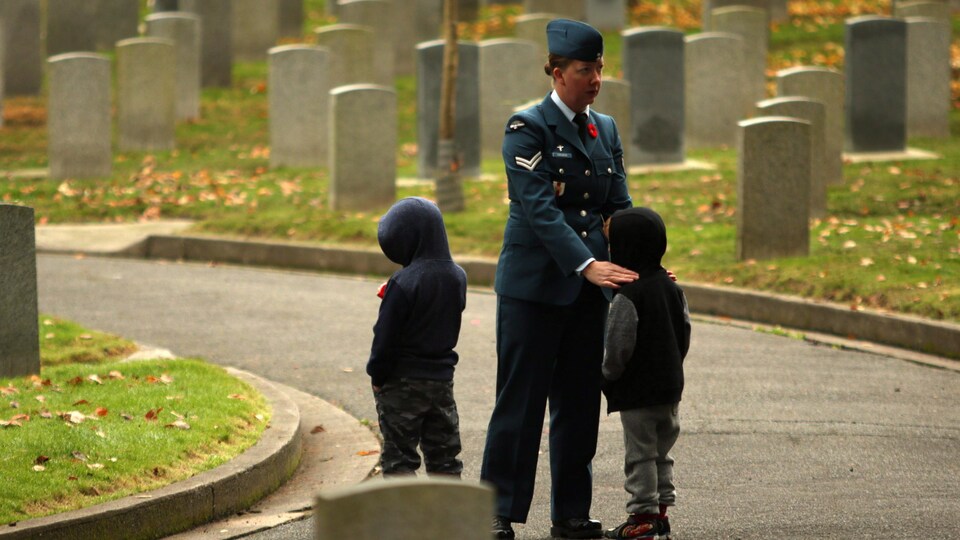 Une caporale des forces aériennes console deux enfants dans un cimetière en Colombie-Britannique.