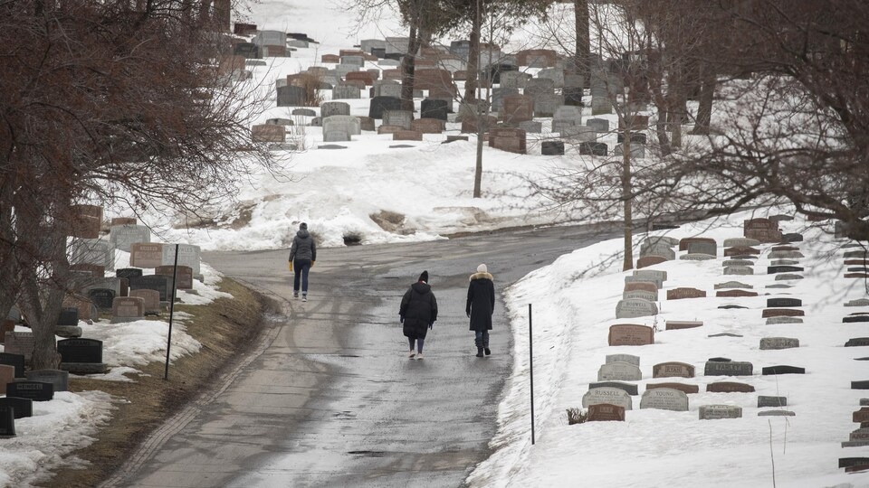 Trois personnes, de dos, marchent au cimetière Mont-Royal.
