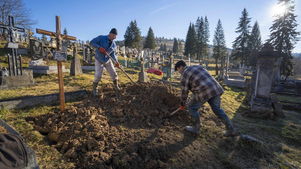 Deux hommes creusent un trou dans un cimetière