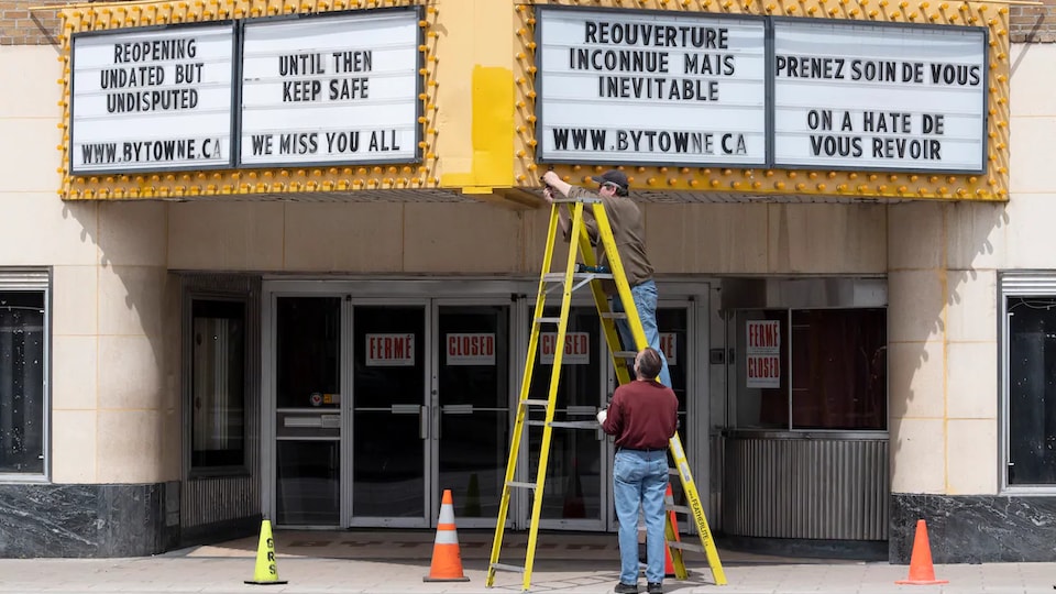 Deux hommes ajustent lamarquise du cinéma ByTowne à Ottawa.