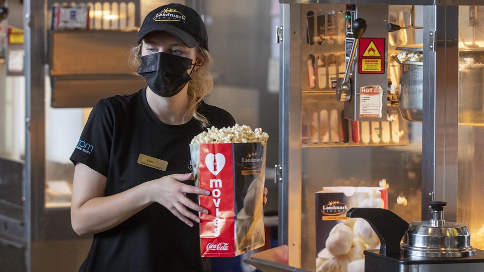 Kaelyn Cherbonneau remet un sac de maïs soufflé à un client au Cinéma Landmark à Kingston.