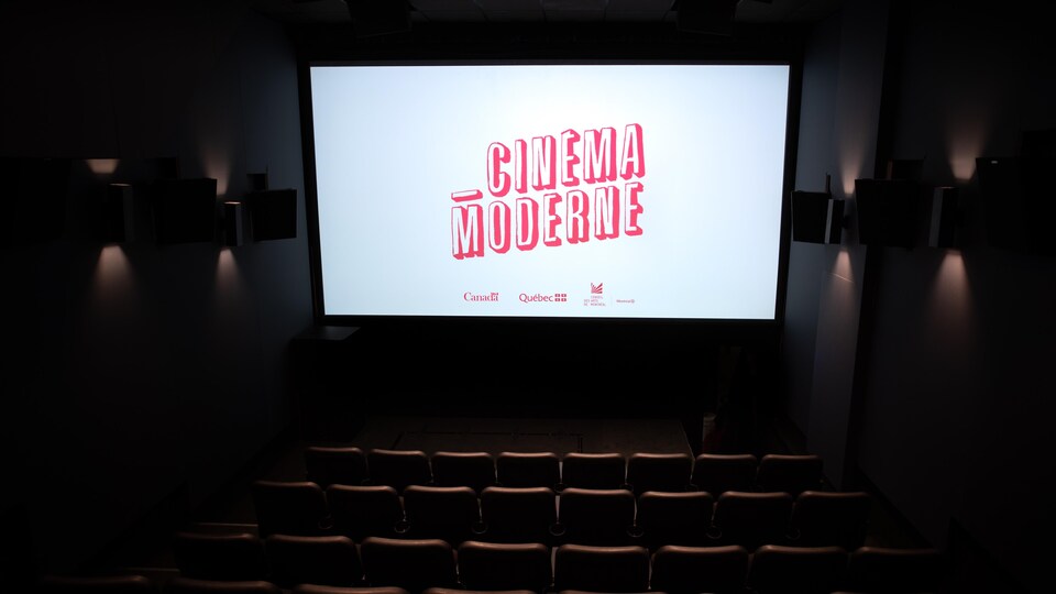 Une salle de cinéma avec quelques dizaines de sièges et un grand écran sur lequel il est écrit «Cinéma moderne».