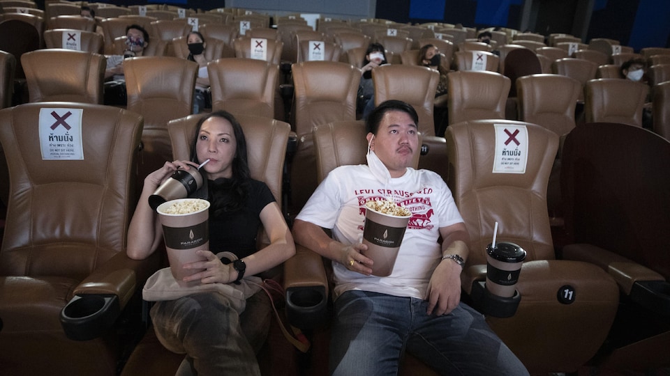Des gens sont assis dans une salle de cinéma en respectant le principe de distanciation sociale.