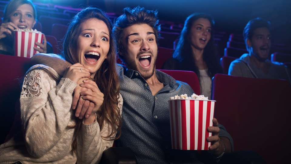 Des gens au cinéma mangent du maïs soufflé.