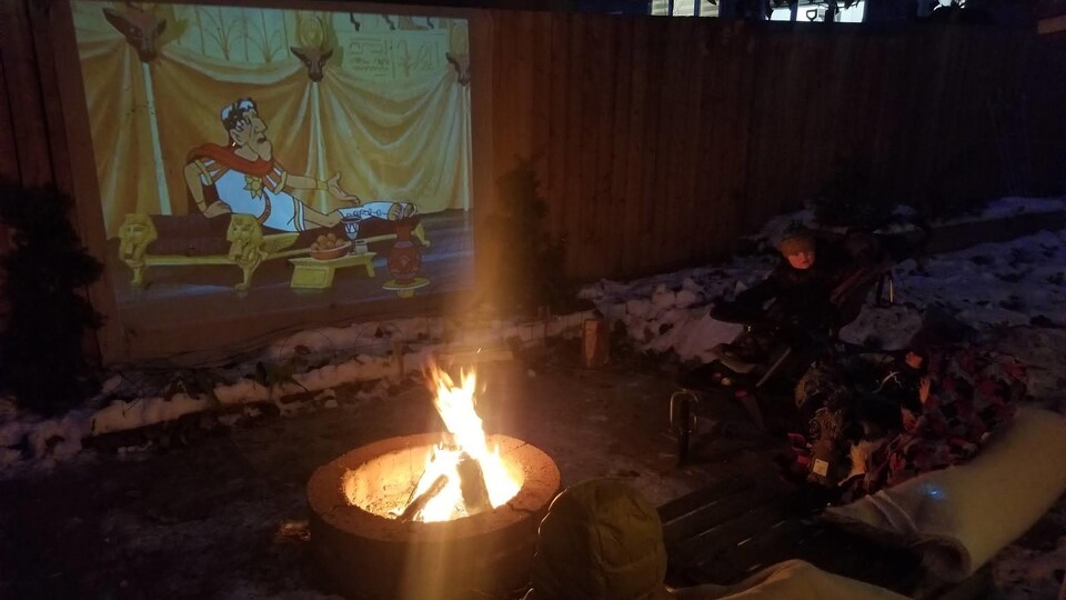 Deux enfants regardent un film près d'un feu.