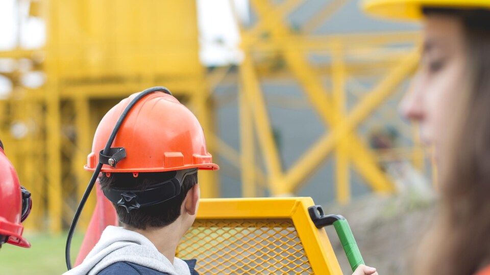 Un enfant portant un casque regarde le site de la Cité de l'Or à bord d'un petit camion.