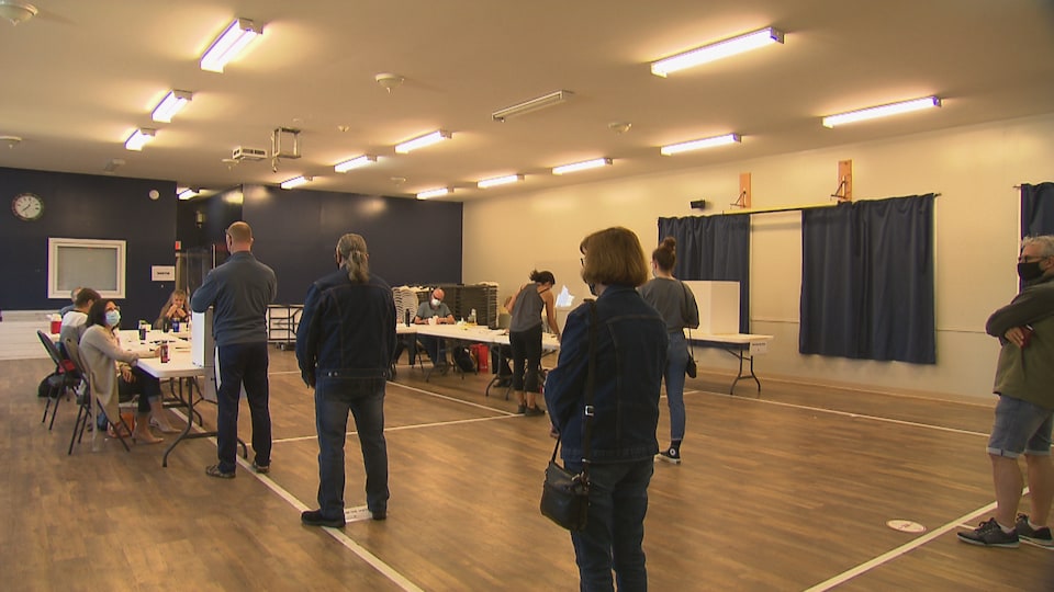Des citoyens en file devant un bureau de vote.