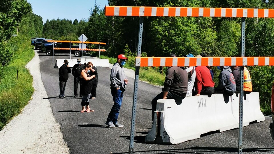 Une dizaine de personnes manifestent sur un ponceau.