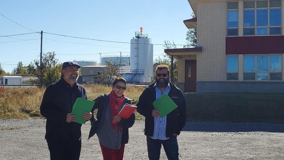 Trois personnes avec des documents lors d'un point de presse devant le terminal de Suncor à Rimouski-Est.