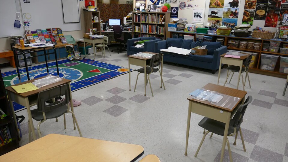 Une salle de classe avec des pupitres qui se trouvent à deux mètres les uns des autres.
