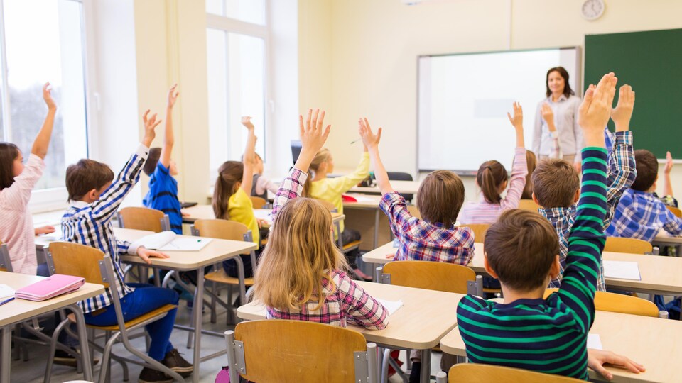 Des élèves lèvent la main dans une salle de classe.