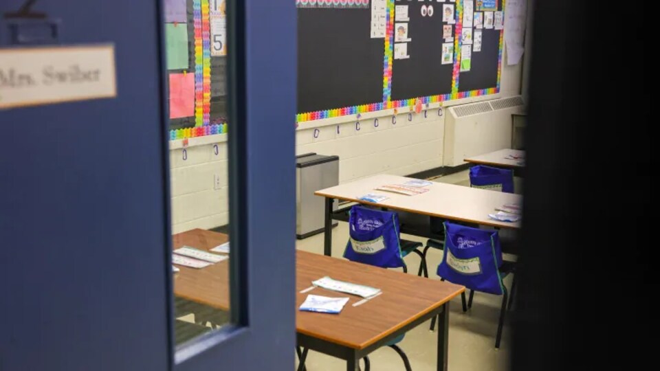 La vue d'une classe vide par une porte entrouverte.
