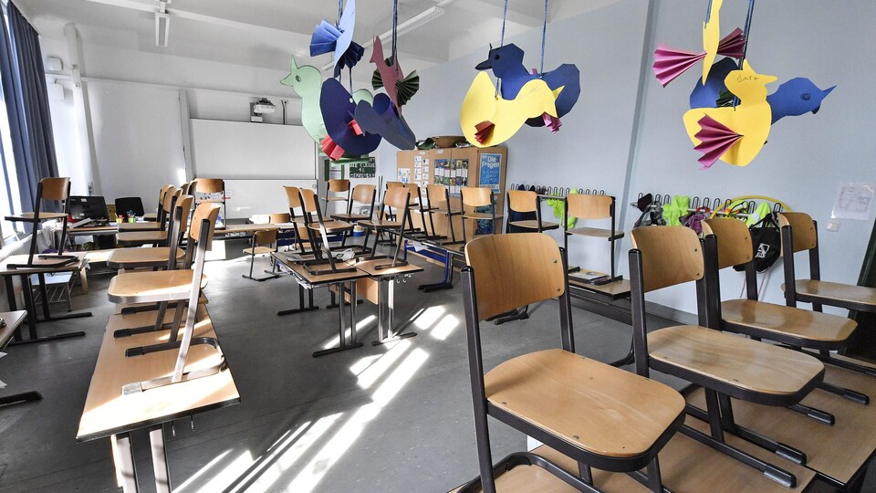 Une classe vide dont les chaises ont été placées sur les pupitres.