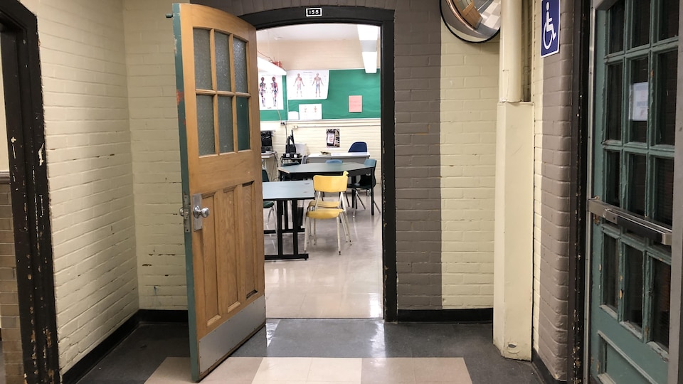 Une porte ouvre sur une salle de classe vide.