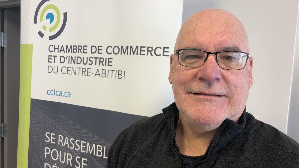 Claude Balleux devant le logo de la Chambre de commerce et d'industrie du Centre-Abitibi.
