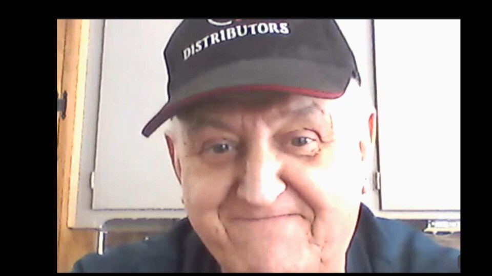 Un homme coiffé d'une casquette en entrevue par webcam.