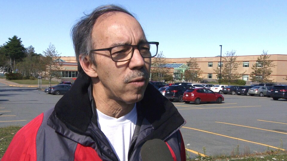 Claude Renaud en entrevue dans un stationnement d'école.