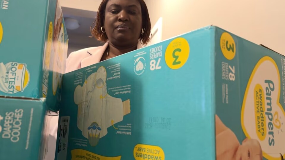 Une femme devant des boîtes de couches pour bébé. 