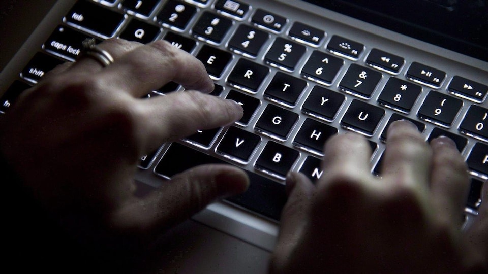 Des mains tapent sur un clavier d'ordinateur.