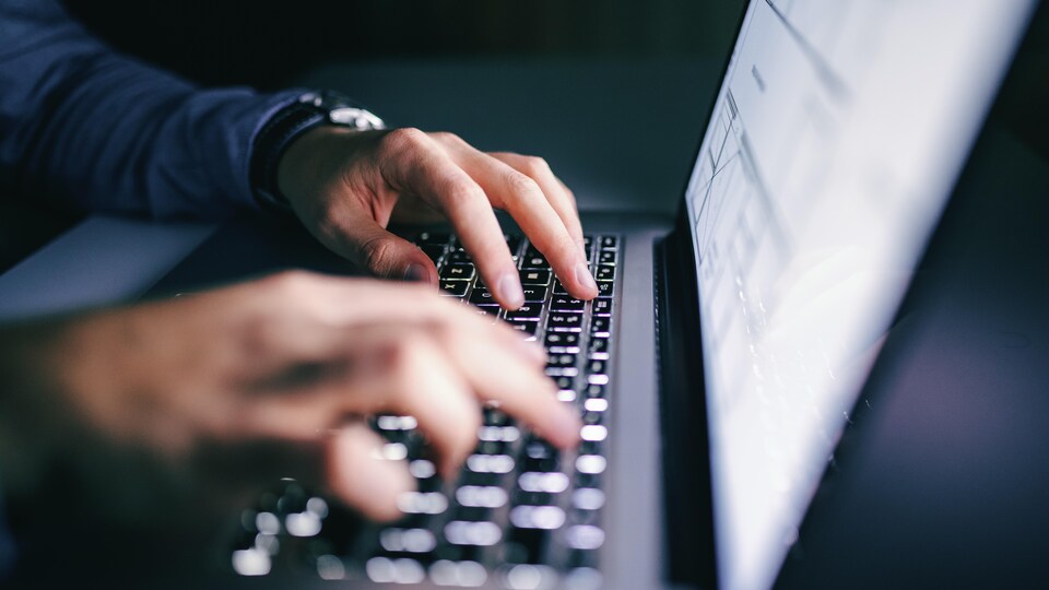 Gros plan de mains sur un clavier d'ordinateur portable.