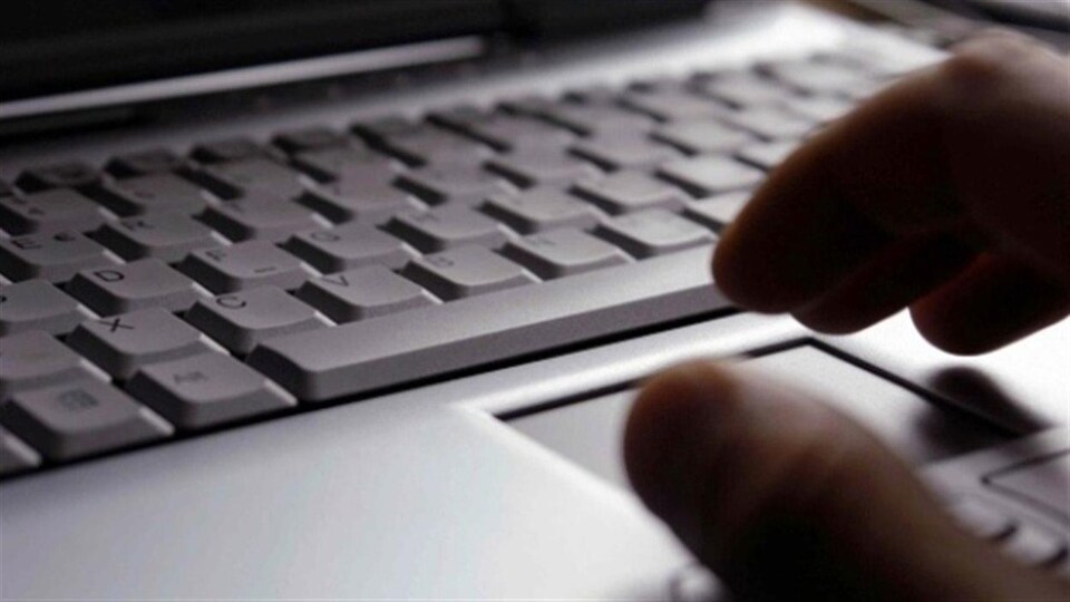 Une main sombre devant un clavier d'ordinateur portable.
