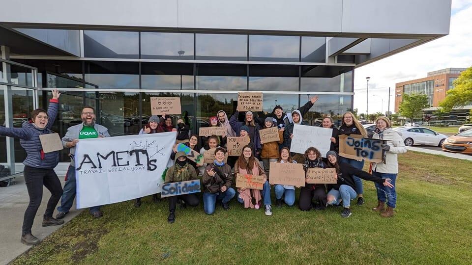 Des étudiants dans une photo de groupe avec leur pancarte devant le campus de Lévis de l'Université du Québec à Rimouski (UQAR).