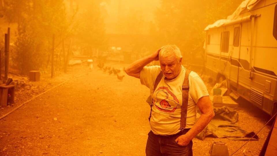 John Cableman, in front of his mobile home in a sepia atmosphere, looks sad.