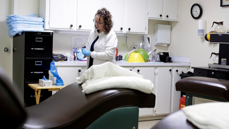Une femme dans une clinique met des gants de plastique.