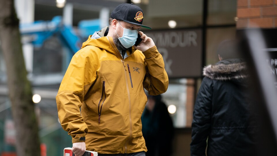 Un jeune homme qui porte un masque marche dans la rue.