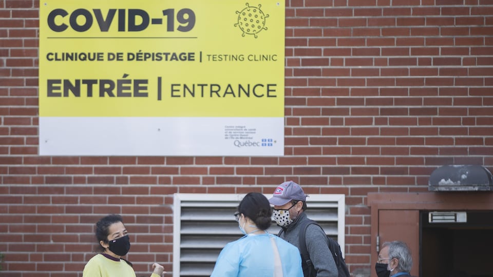 Des gens attendent devant un centre de dépistage de Montréal.