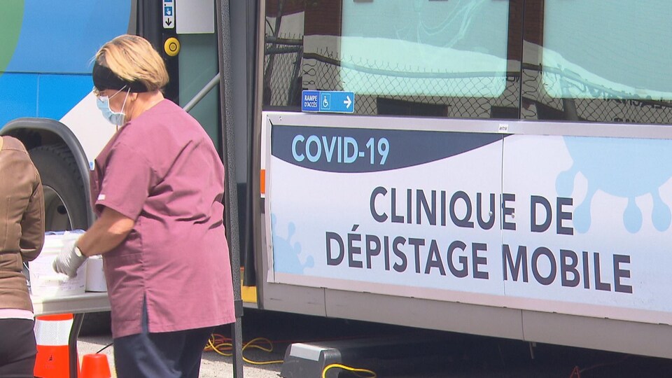 Une infirmière devant un autobus consacré aux tests de dépistage.