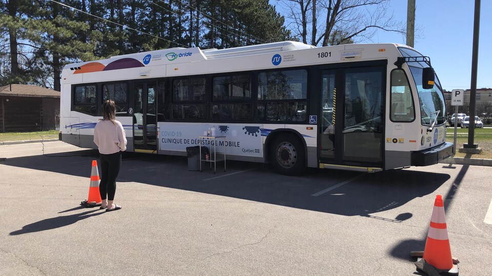 Un autobus à l'intérieur duquel des tests de dépistage de la COVID-19 peuvent être menés est garé dans un stationnement.
