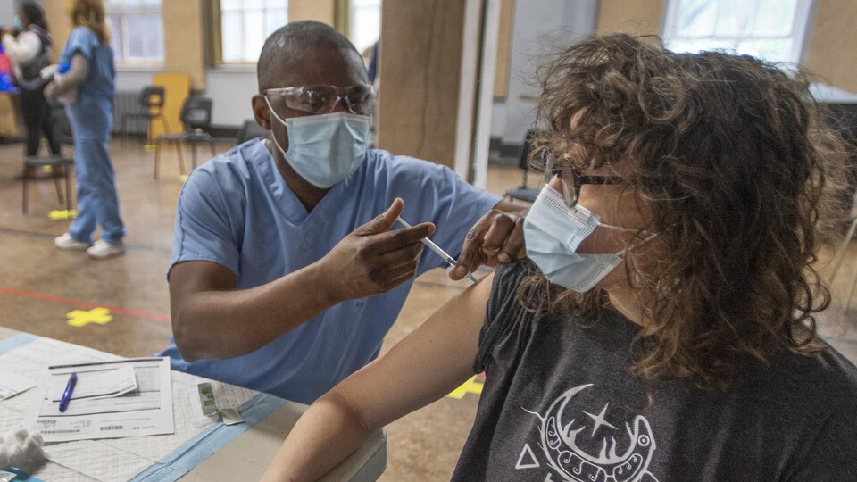 Un infirmier injecte le vaccin dans le bras de la patiente.