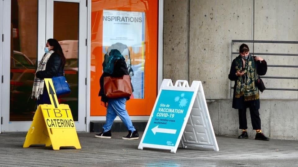 Des gens attendent devant un site de vaccination, à Montréal.