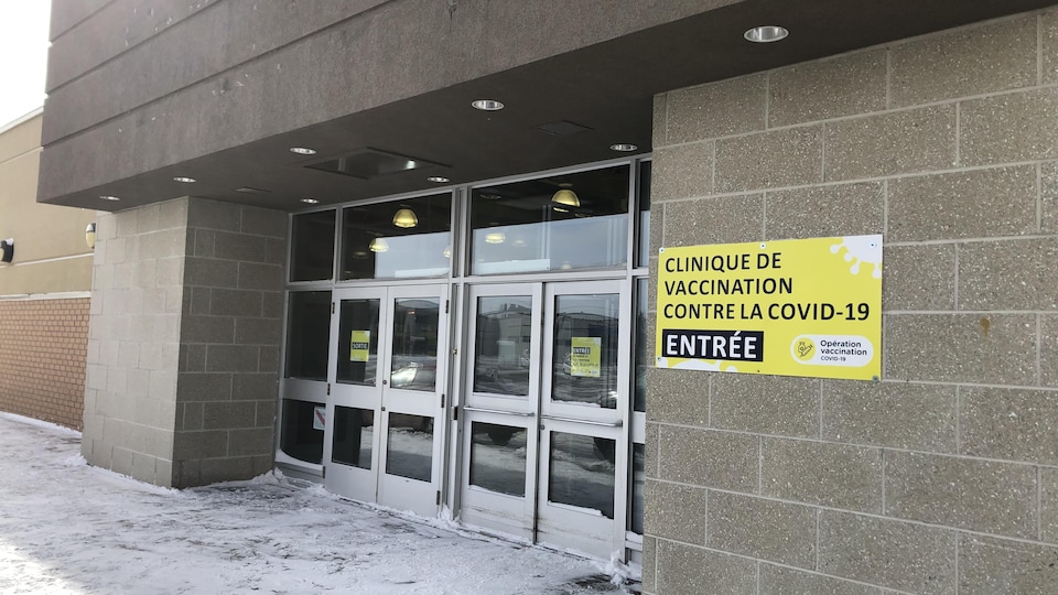 Une pancarte jaune indique l'entrée d'une clinique de vaccination.