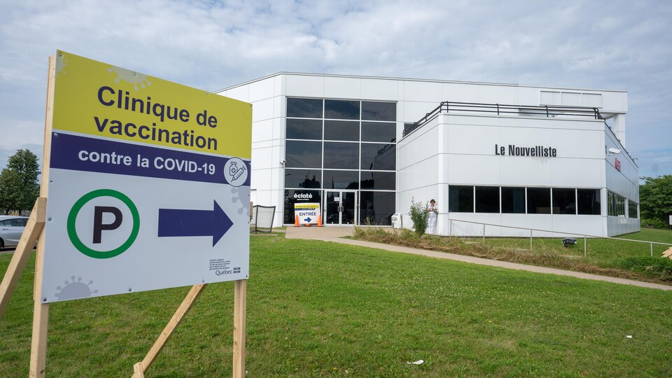 Un panneau devant un bâtiment indique la présence d'une clinique de vaccination.