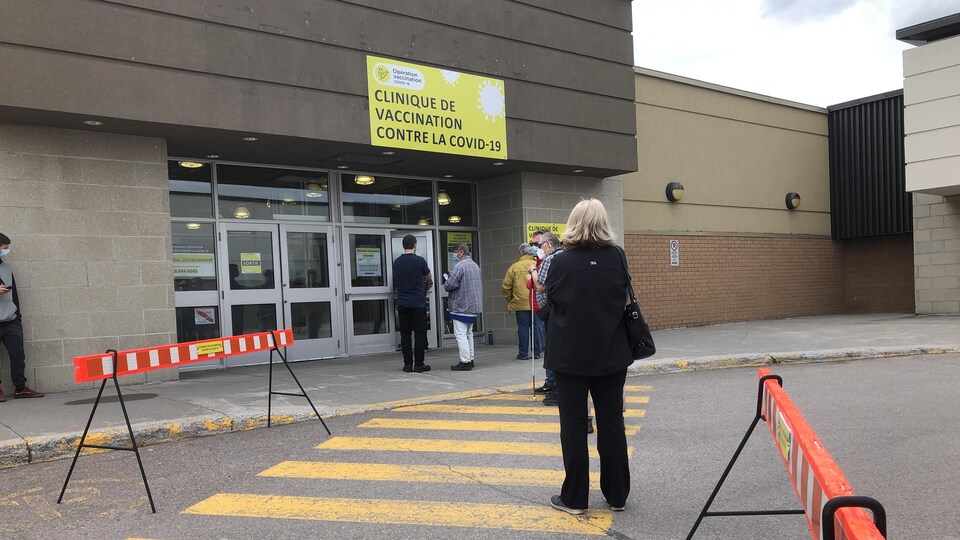 Des citoyens attendent pour entrer dans le centre de vaccination.