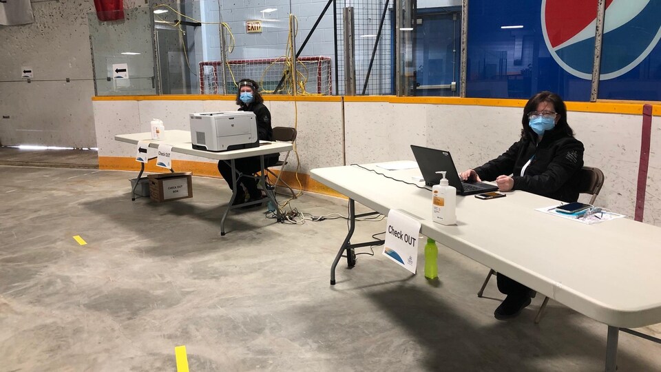 Deux personnes sont assises à deux bureaux.