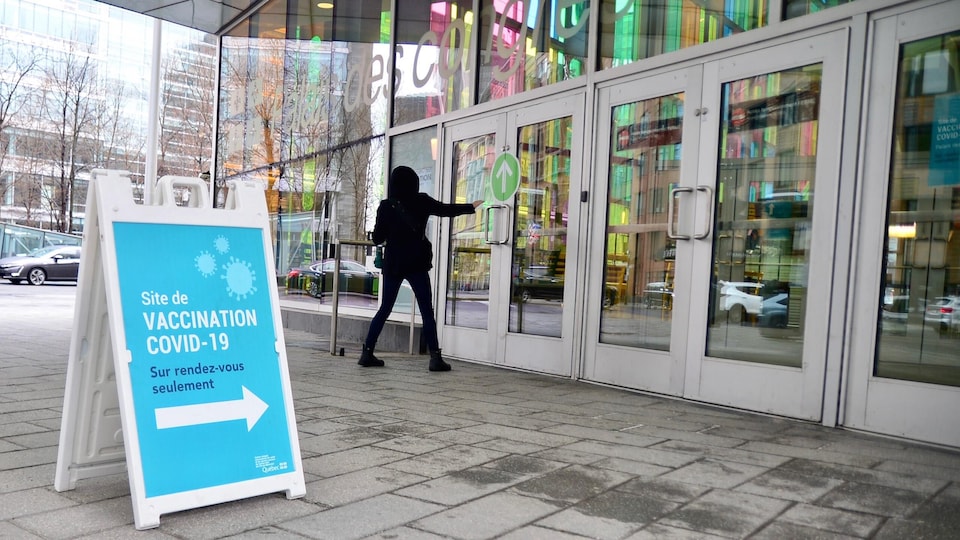 Une personne ouvre la porte de l'entrée d'une clinique de vaccination à Montréal.