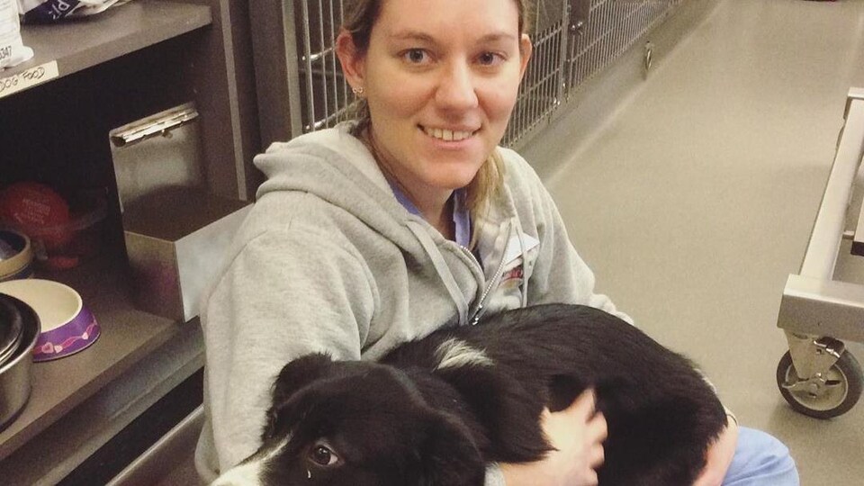 une femme assise en tailleur avec un chien sur les genoux dnas une clinique vétérinaire.