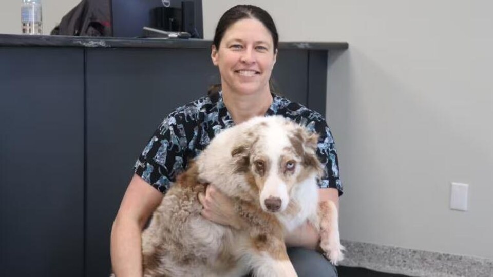Une femme tient un chien dans ses mains.